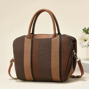 Detailed close-up of vertical striped woven handbag with brown leather flap and gold hardware
