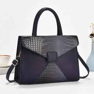 Détail du sac bleu marine montrant le mélange de textures de cuir et la boucle en métal doré