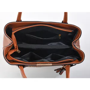 Interior view of brown leather handbag featuring multi-compartment storage and gold zippers