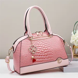 Close-up of pink embossed crocodile pattern bag with golden hardware and charm detail