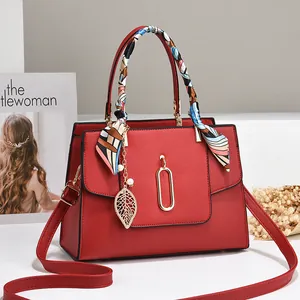 Borsa a mano rossa in pelle con foulard di seta e ciondolo a foglia dorata di classe