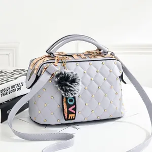 Sac à main matelassé lavande avec rivets dorés et pompon décoratif en fourrure