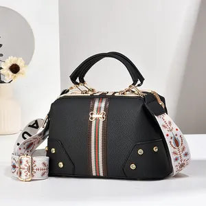 Détail du sac docteur en cuir noir avec bandes rouge-vert et boucle dorée en nœud