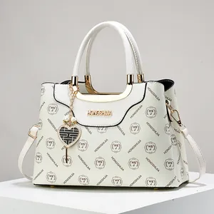 Sac à main blanc à monogramme avec poignées dorées et breloque en cœur