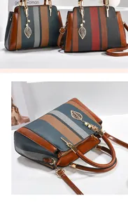 Detail der kontrastfarbenen gestreiften Handtasche mit Webstruktur und goldenem Blatt