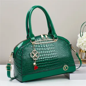Detail of green crocodile embossed faux leather bag with gold heart clover charms