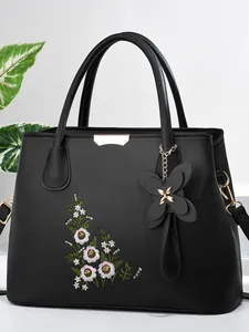 Chic black faux leather handbag with floral embroidery and butterfly pendant accessory