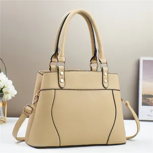 Detail of beige lychee leather tote showing golden rivets and black edge paint finish
