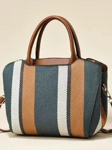 Vertical striped canvas tote bag with woven texture and brown leather handles in flat lay view