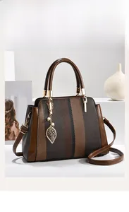 Nahaufnahme der Retro-Streifen-Handtasche mit Blatt-Anhänger und feiner Lederstruktur