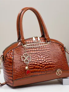 Sac à main marron avec gaufrage crocodile, détails dorés et pendentif trèfle élégant