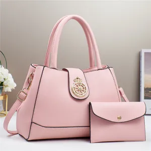 Dettaglio borsa rosa in pelle PU a grana di litchi con emblema dorato e mini pochette