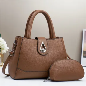 Detail of brown pebble grain leather tote set with silver teardrop clasp and shoulder strap
