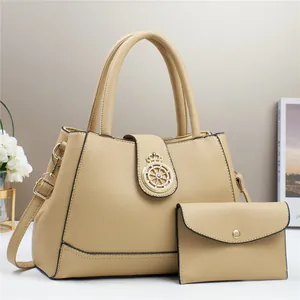 Dettaglio della borsa a mano beige in pelle martellata con decorazione corona in metallo