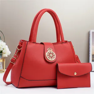 Dettaglio del set tote in pelle rossa con emblema dorato e pochette coordinata inclusa