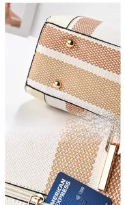 Details goldener Bodennieten und Metallreißverschluss der gestreiften Lederhandtasche