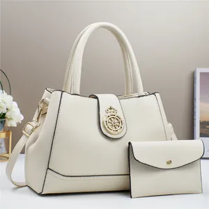 Dettaglio della borsa tote color crema con fibbia a corona dorata e mini pochette coordinata