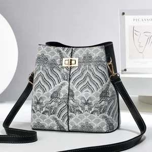 Detail of printed bucket bag with jacquard fabric pattern and gold twist lock closure
