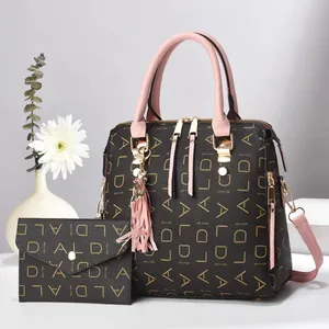 Detail view of the brown monogram tote and pink tassel charm with a matching wallet