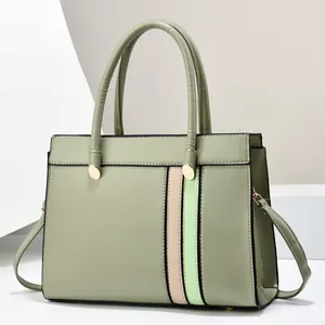 Detail view of sage green tote bag with contrast pink stripes and gold hardware accents