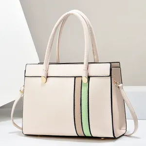 Detail view of cream white tote bag with beige and green contrast stripes and gold hardware