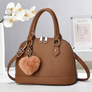Detail of brown litchi pattern shell bag featuring double zippers and plush heart charm