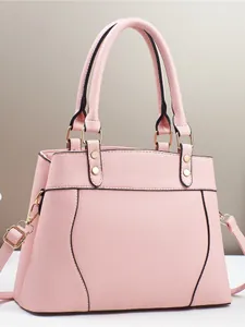 Pink lychee texture handbag with gold hardware and adjustable strap on a neutral background