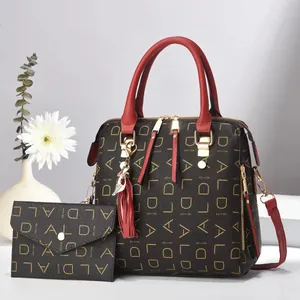Detail of dark brown tote and envelope wallet set with gold lettering and red fringe charm