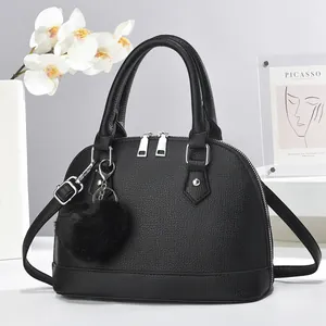 Close-up of black litchi grain shell bag with silver dual zippers and fuzzy ball charm