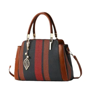 Handtasche mit Kontrastfarben, dunkelgrauen Streifen und goldenem Blattanhänger