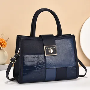 Detail of color-block tote bag with mixed crocodile and lizard textures and metal lock