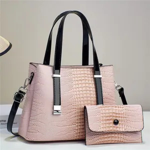 Detail of pink croc-embossed tote bag set with black contrasting handles and silver hardware