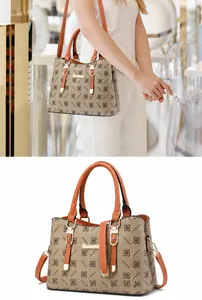 Detail of monogram handbag featuring orange handles and a detachable shoulder strap