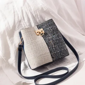 Détail du sac bandoulière tissé bleu et beige avec fermoir anneau doré et surpiqûres