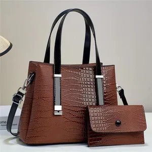 Detail of brown crocodile pattern tote bag set with textured leather and silver hardware