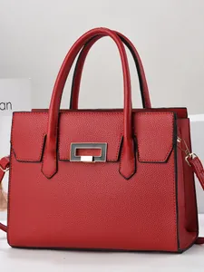 Elegant red pebbled leather tote bag with gold buckle on a minimalist display stand