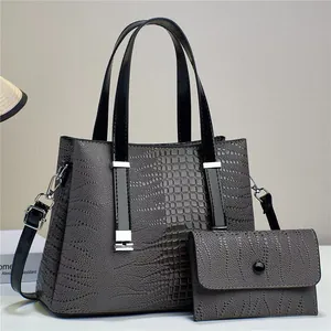 Macro shot of dark grey crocodile pattern handbag and matching wallet with silver hardware
