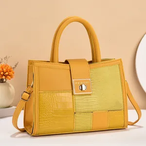 Detail of yellow patchwork tote with crocodile texture and gold metal clasp closure