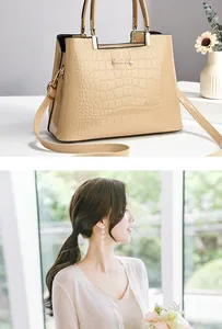 Detalle de bolso beige con grabado de cocodrilo, logotipo metálico dorado y asa superior