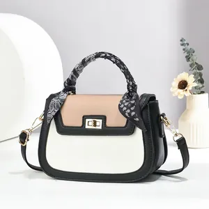Detailed close-up of a contrast leather handbag with silk scarf handle and gold lock