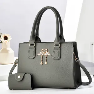 Detalle del bolso tote gris oscuro con herraje de cisne dorado y borla de perlas