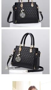 Close-up of black handbag with geometric texture, gold hardware, and clover charm