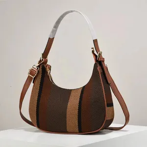 Striped hobo shoulder bag with brown leather trim and adjustable strap on a white stand