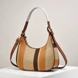 Striped canvas half-moon shoulder bag with brown leather trim on minimalist display