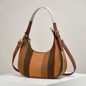 Striped knit hobo bag with brown leather strap and gold hardware on white pedestal