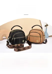 Detail view of semi-circular leather bags with wide floral straps and gold hardware