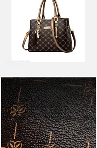 Detail of lychee textured leather and metal ring handle on dark brown handbag