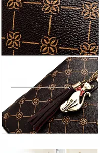 Detail of lychee pattern leather and gold floral print with cat charm and tassel