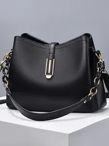 Sac seau noir en cuir litchi avec fermoir doré et bandoulière chaîne sur plateforme
