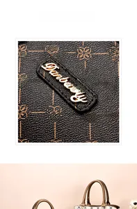 Detail of golden Danbaoly logo plaque on textured floral vintage shoulder bag